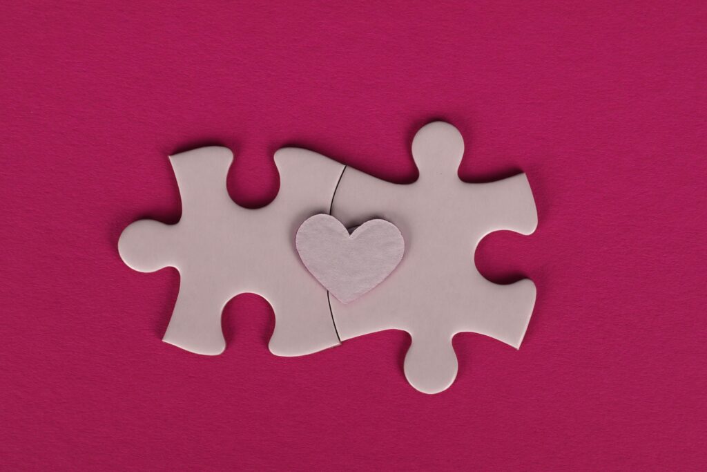 Two puzzle pieces with a heart shape in between, symbolizing connection and love.