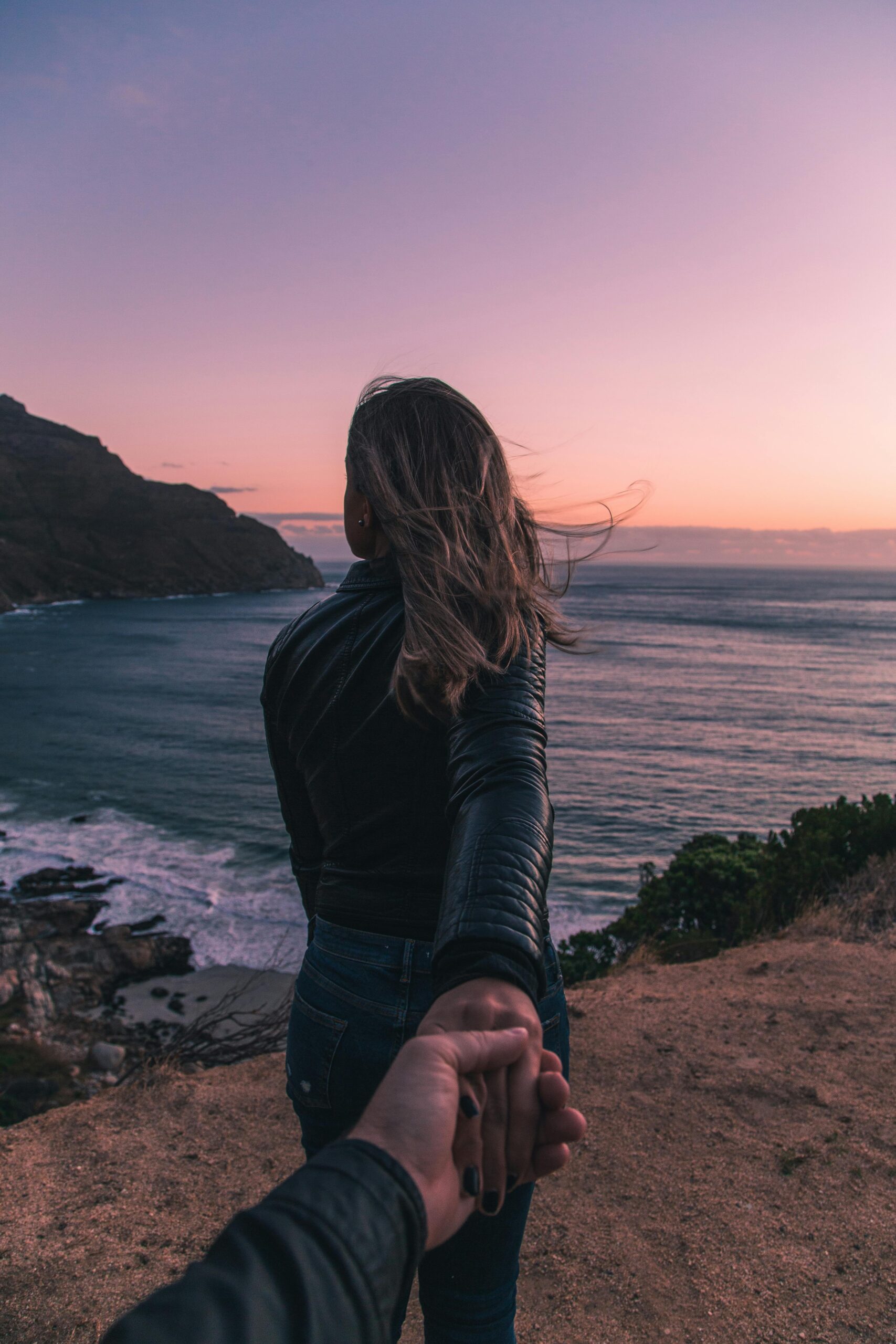 Young couple holding hands by the ocean with a stunning sunset view in Cape Town.