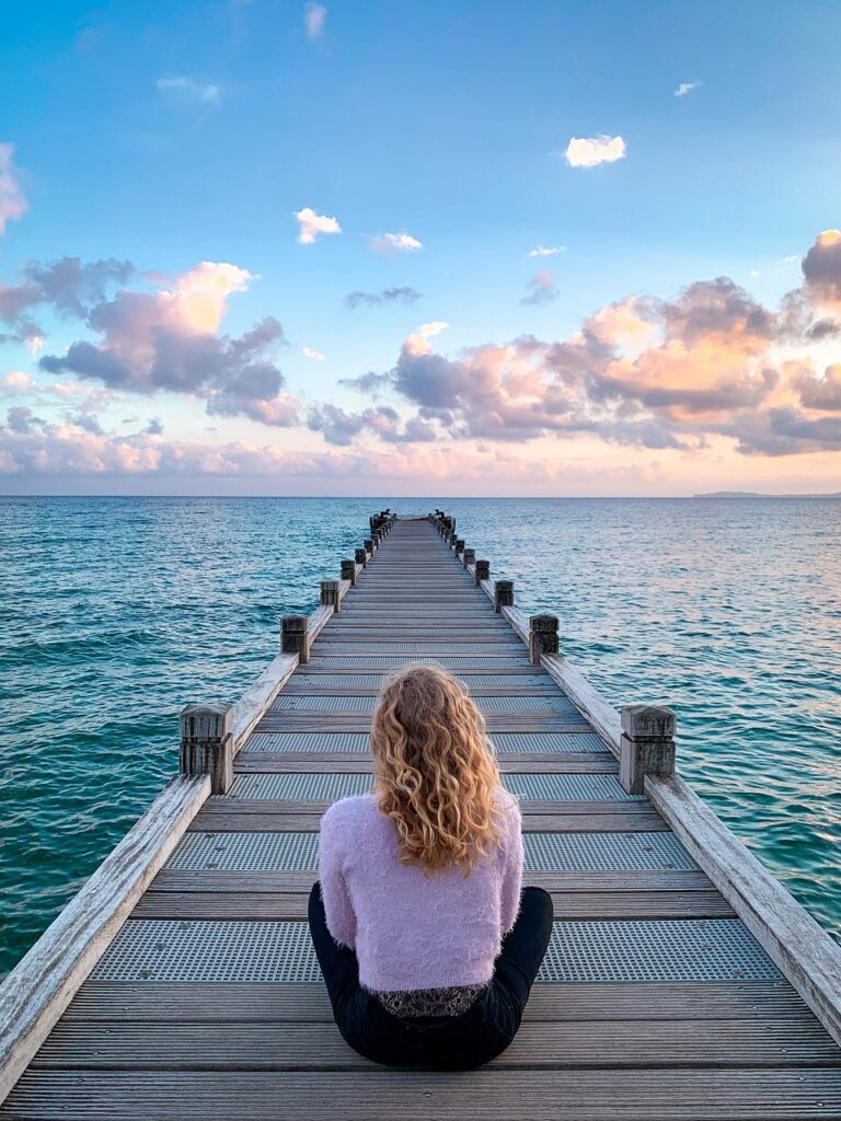 woman meditating on a pier; lake