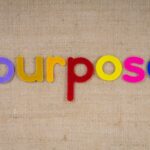 Colorful felt letters spelling 'purpose' on a textured fabric background with ample copyspace.