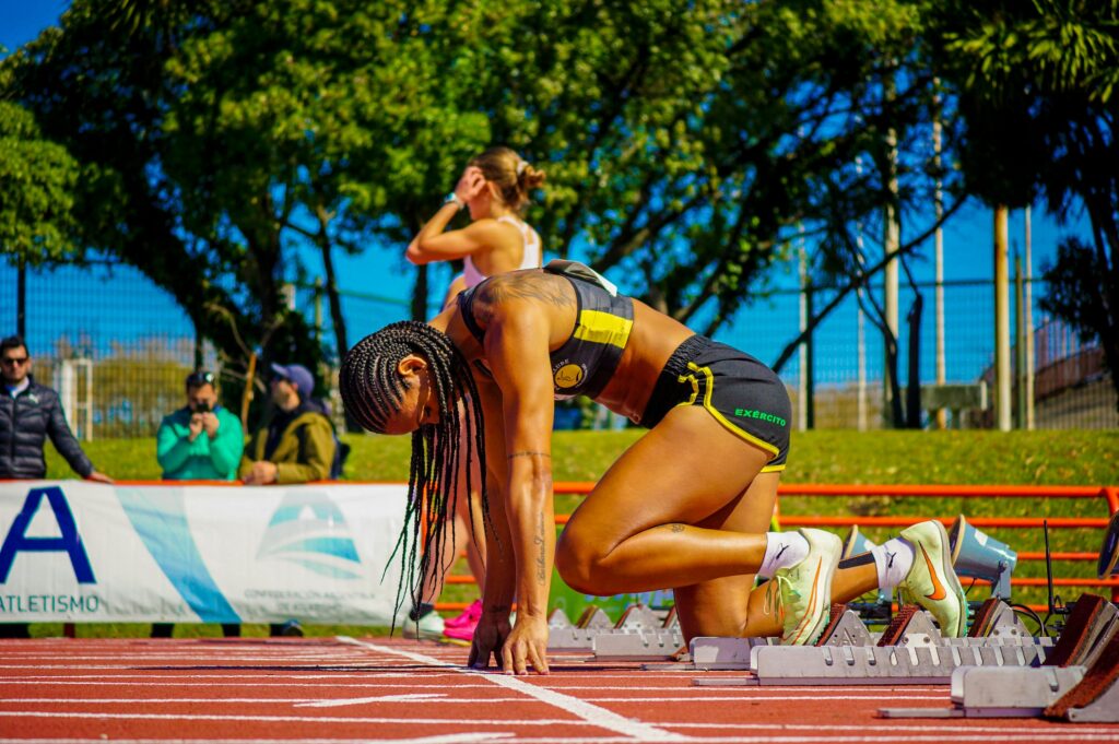 Focused female athlete in starting position on track, ready to compete.