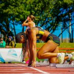Focused female athlete in starting position on track, ready to compete.