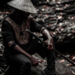 A dramatic outdoor portrait of a man holding a samurai sword, wearing traditional attire with a hat.