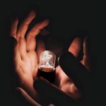 Closeup of anonymous person demonstrating burning lightbulb in palms in middle of darkness